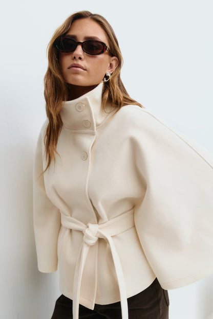 Women's funnel neck cape sleeve draped coat in white, side view